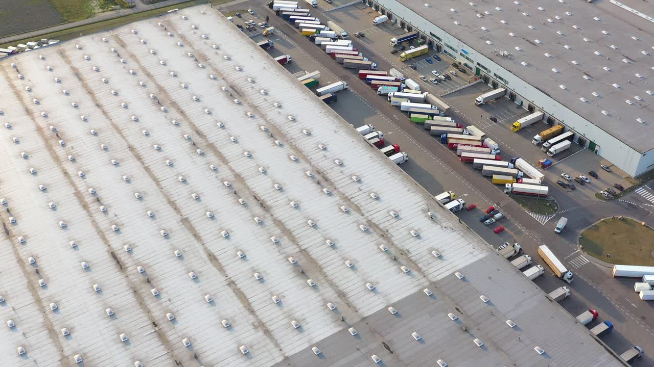 Lastbil med sættevogn kører langs en parkeringsplads ved et lager i logistikparken.