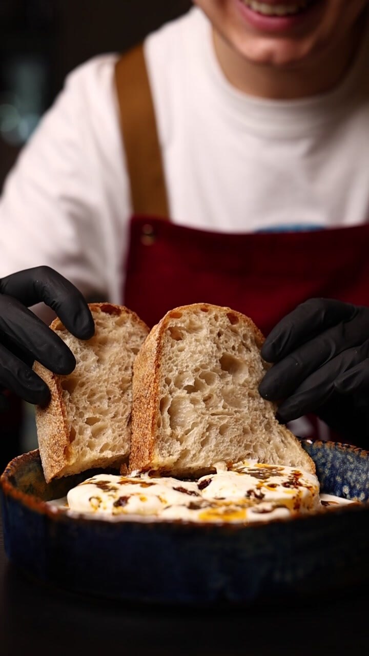 Chef Holding Slices of Fresh Sourdough Bread Over a Dish