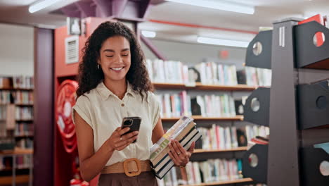 woman in library using phone and holding books