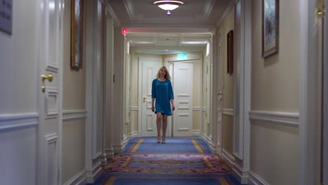 beautiful woman in blue dress walking along corridor at luxury mansion