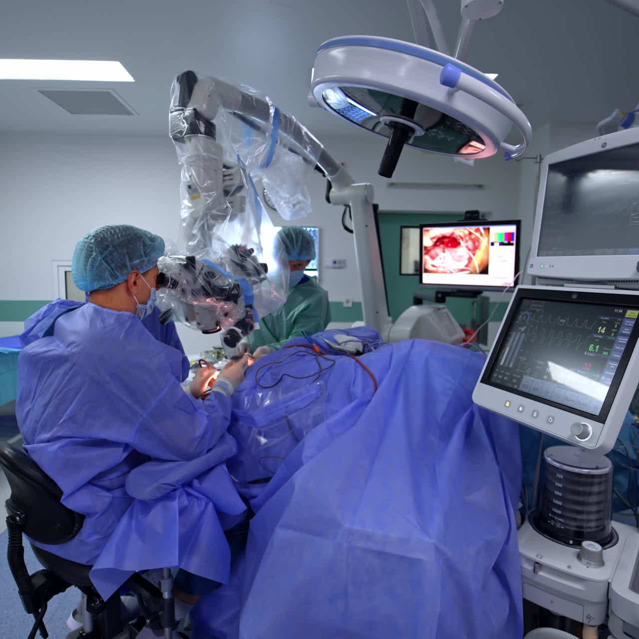 Modern neurosurgical operation using advanced microscope. Sitting doctor applies medical instruments which is shown at the screen at backdrop