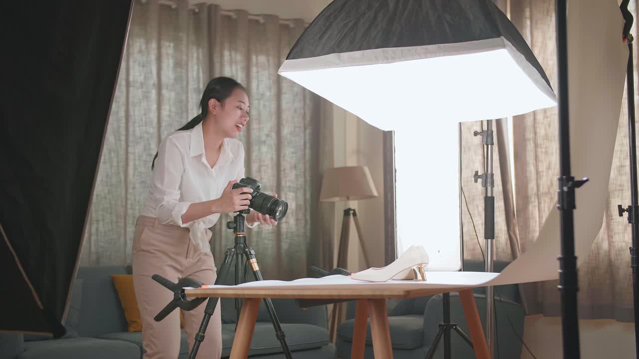 fotógrafa asiática ajustando la posición de los zapatos de las mujeres mientras toma fotos de ellos en su estudio casero
