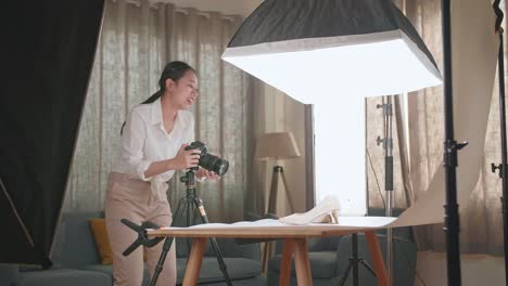 asian female photographer adjusting position of women's shoes while taking photos of them in home studio