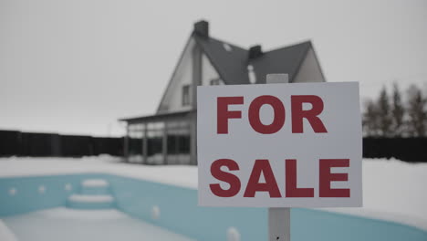 person putting for sale banner on a house