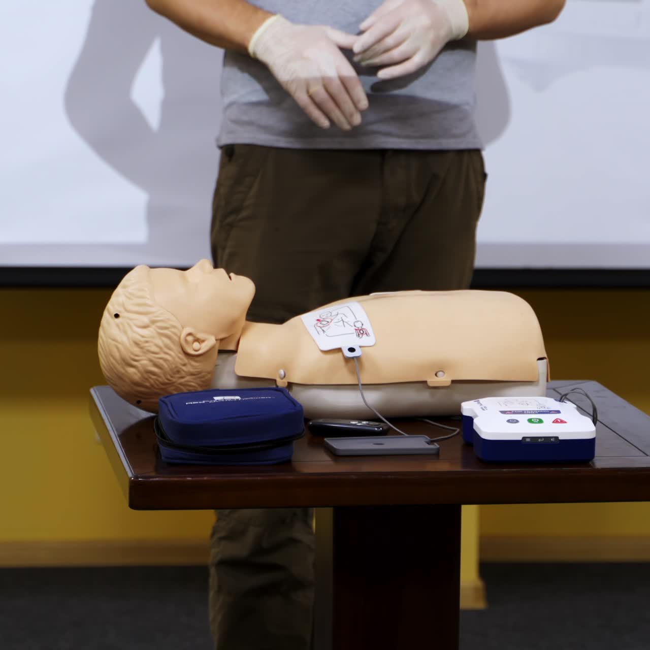 Trainer teaching medical skills on a mannequin. Instructor showing practical methods for giving first aid on a dummy. Healthcare and medical concept