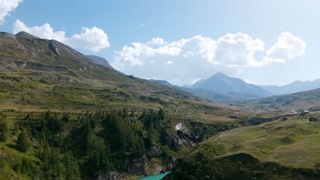 Eine-Atemberaubende-Luftaufnahme-Des-Mont-Cenis-Sees,-Umgeben-Von-Bergigem-Gelände-Und-üppigem-Grün-Unter-Einem-Klaren-Himmel