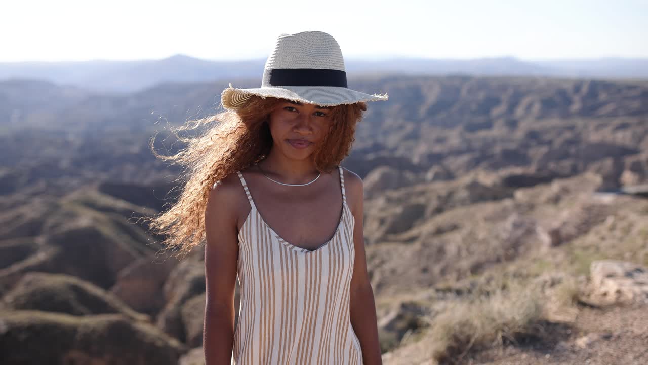 Woman in a straw hat standing in a desert landscape