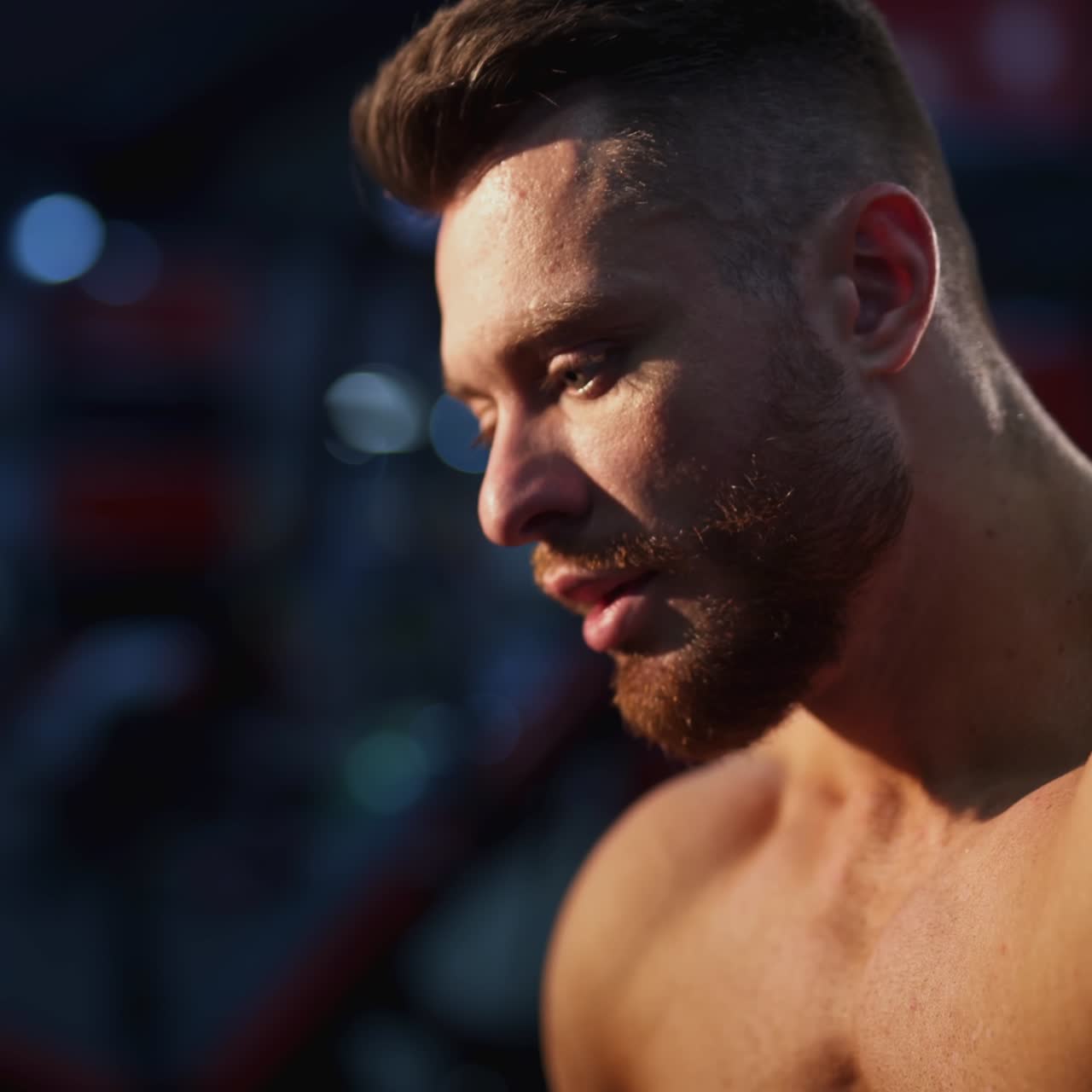 Handsome sportsman resting after hard training. Portrait of a young shirtless athlete breathing hard after doing workout in the gym. Close-up