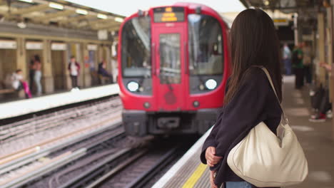 junge frau mit handy wartet auf dem bahnsteig der u-bahn, als der zug ankommt 1