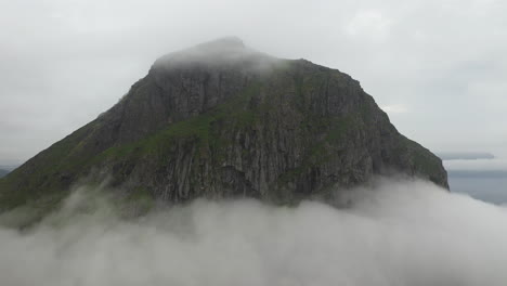 epic drone shot of mountainside with clouds surrounding the base and summit, vik beach hauklandstranda norway