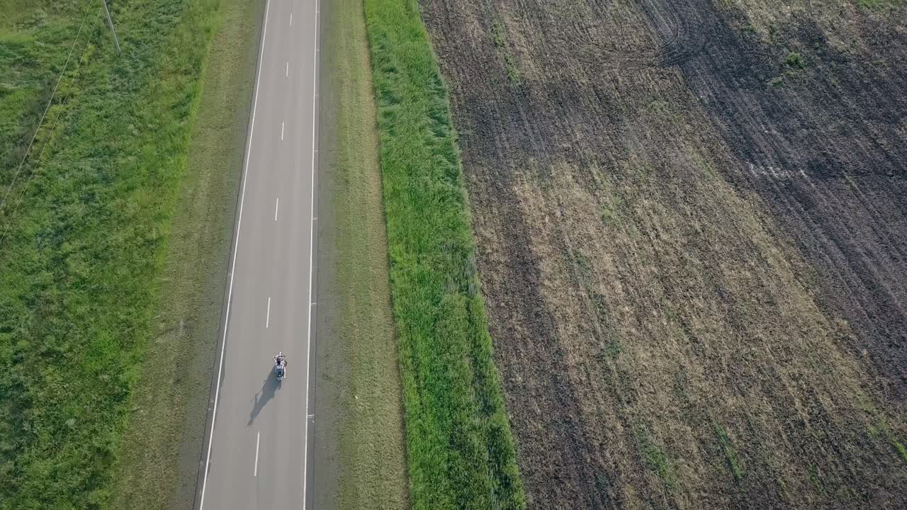 vuelo sobre la carretera que corre entre el prado y el campo arado