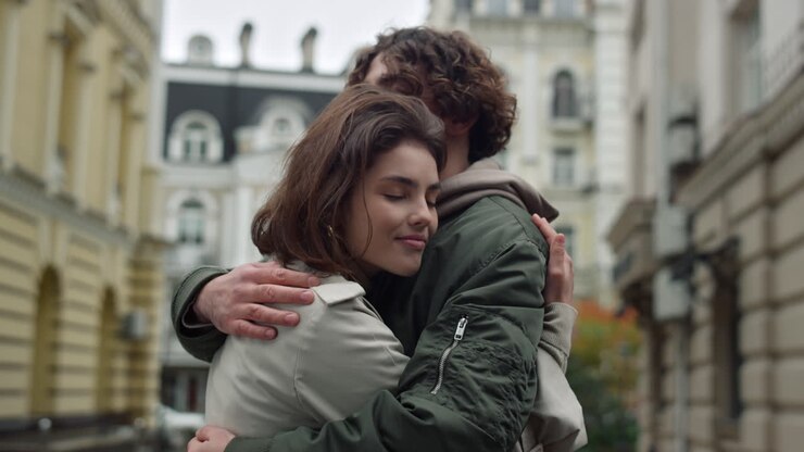 Lovely couple hugging on street. Happy girlfriend leaning to boyfriend outdoor.