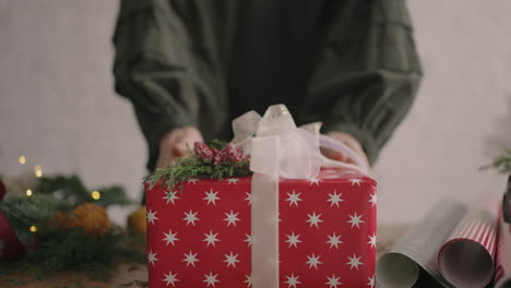 the camera follows the gift. a woman with her hands pushes a christmas box with decorations into the camera. green christmas gift made with your own hands from eco-friendly materials