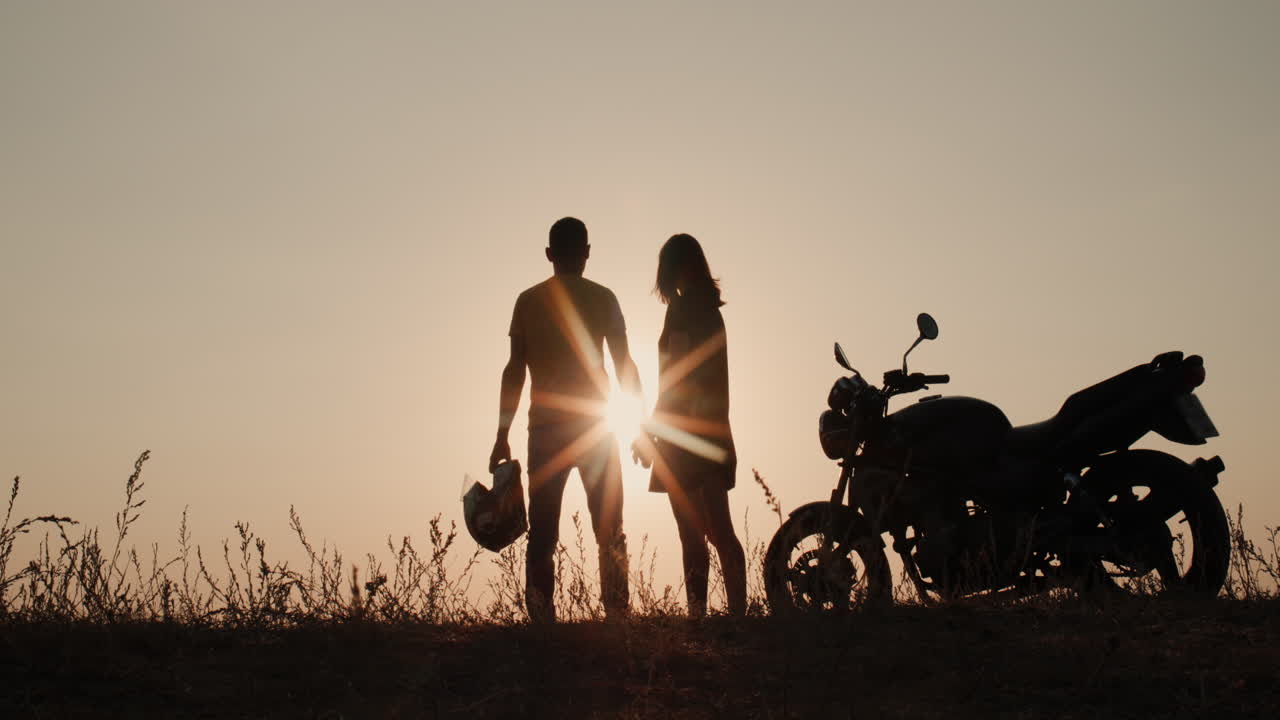 오토바이 근처의 젊은 부부의 실루엣