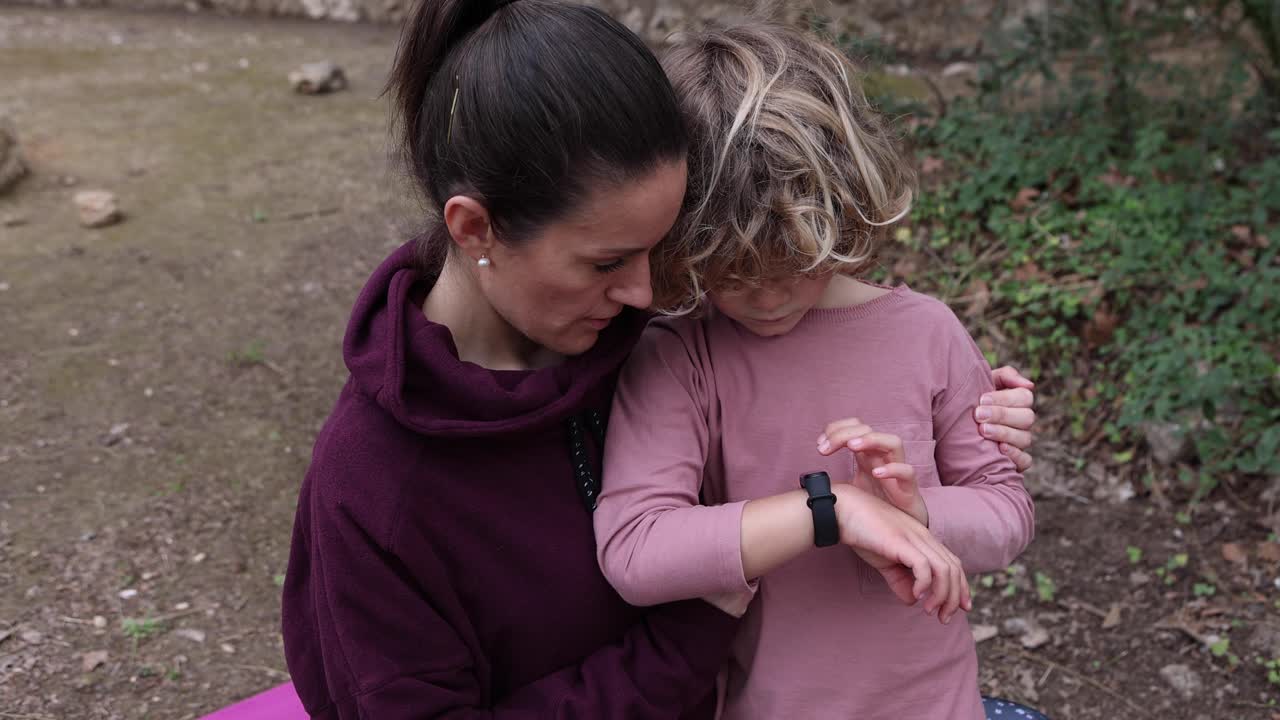 mamá explicando a su hijo cómo usar un reloj de pulsera al aire libre