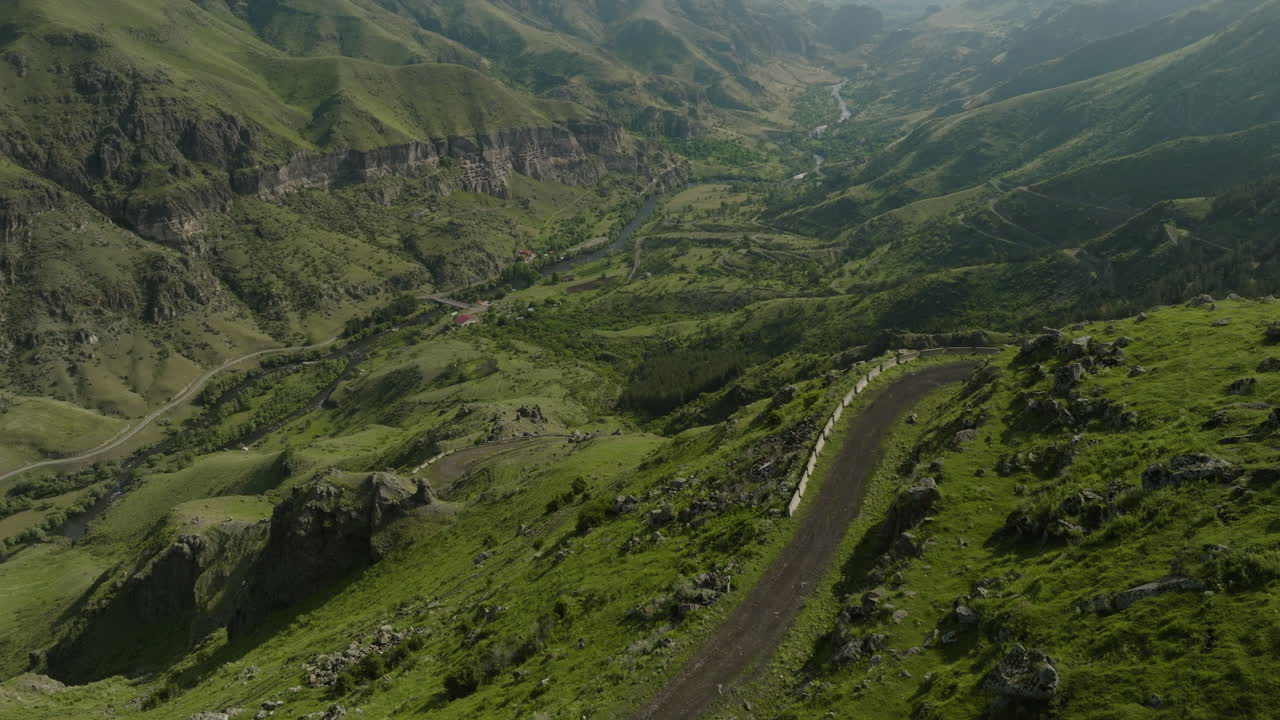 Panorama di catena montuosa verde con strada sterrata nelle prime ore del mattino in Georgia