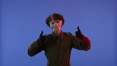 man in white mask pointing fingers up on blue background with red neon light image of jason voorhees