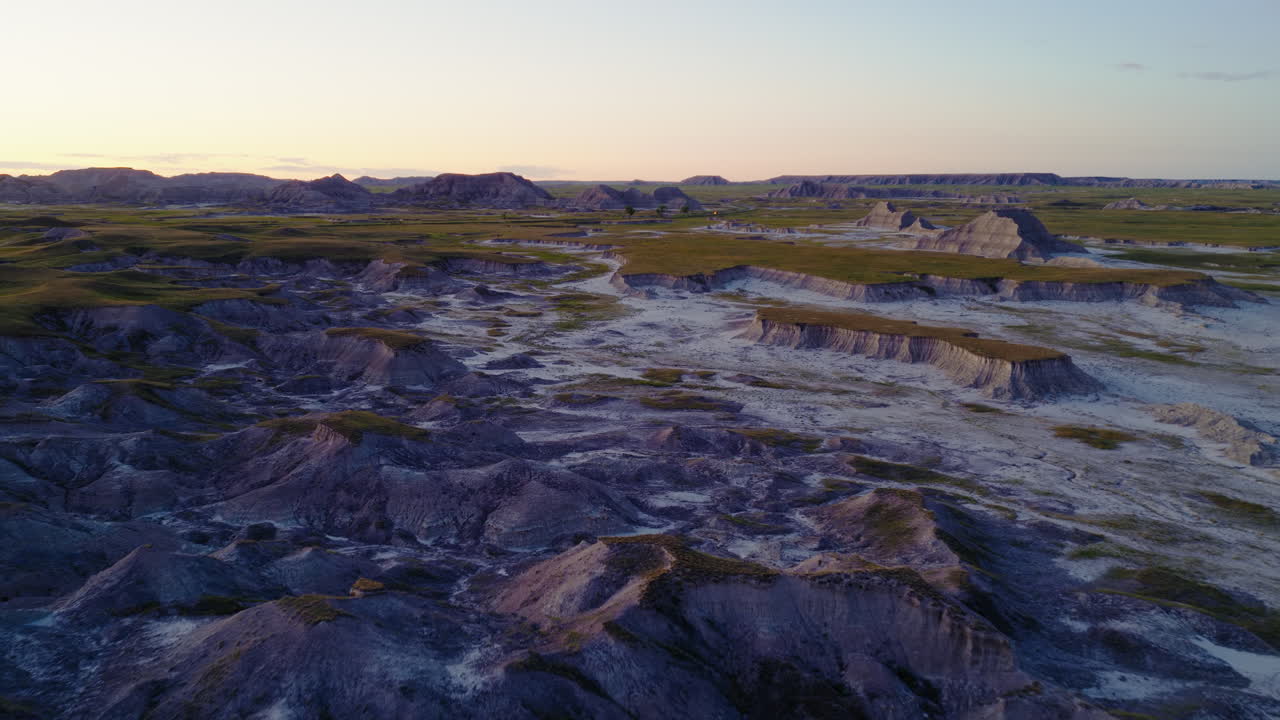Evening Glow Spreading Across Rugged Badlands Landscapes by Drone