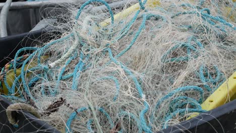 tangled box filled with fishing nets mesh and rope packed in harbour marina crate dolly left