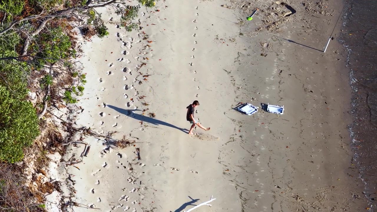 Giovane uomo che cammina lungo una spiaggia tropicale