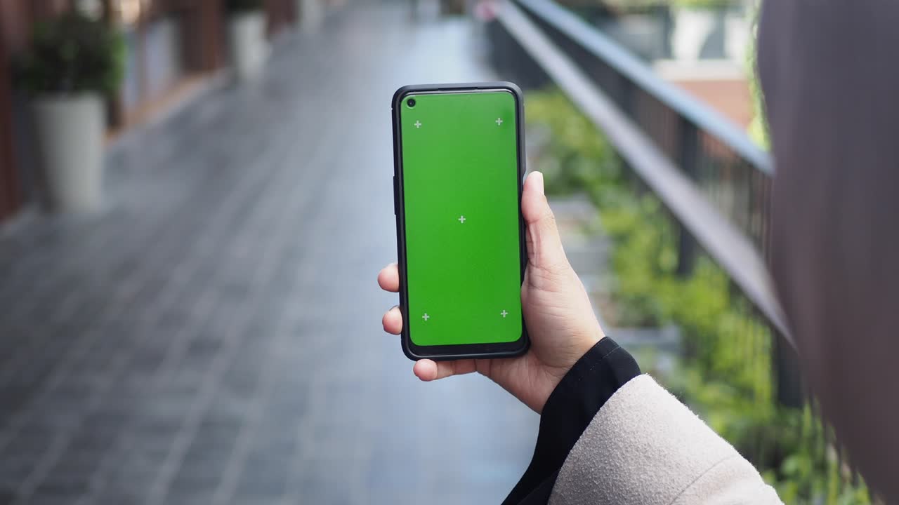 Person Holding Smartphone with Green Screen and Tracking Markers