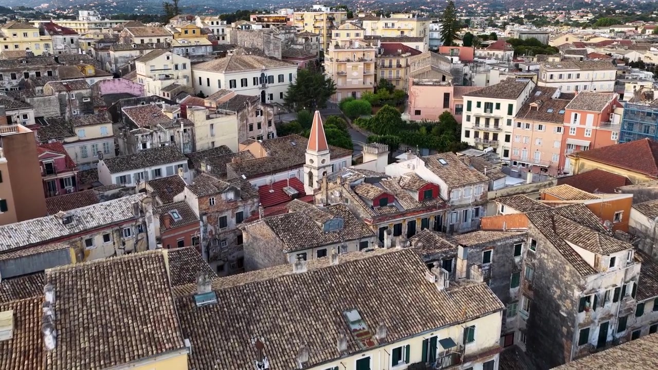 Volo aereo con drone sopra i tetti storici della città vecchia di Corfù e l'architettura veneziana colorata nella tenue luce del primo mattino, isola di Kerkyra, Mar Ionio, Grecia