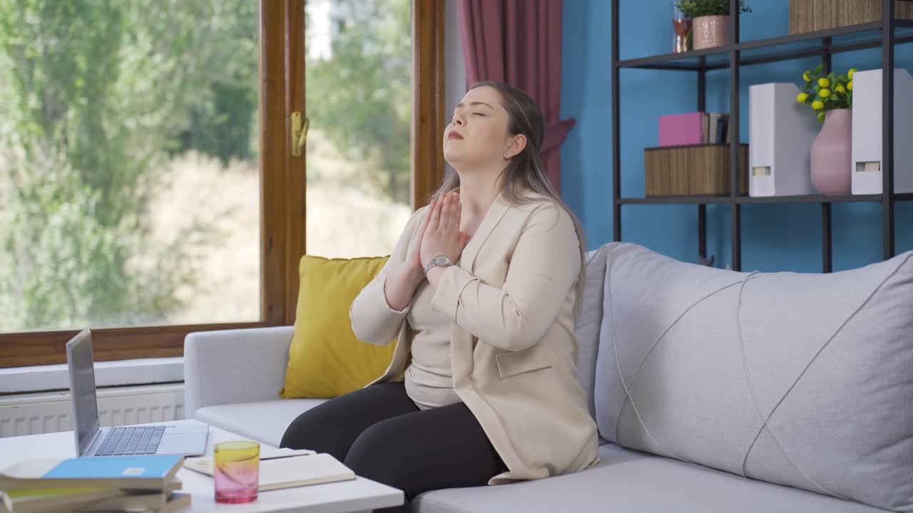 창문 앞에서 기도하는 젊은 기독교 여성.