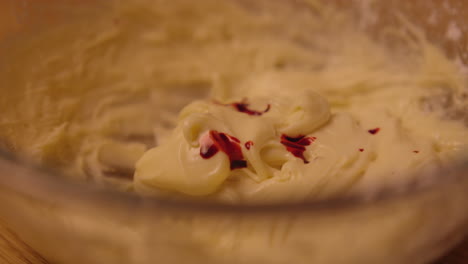 mixing white frosting with red food coloring