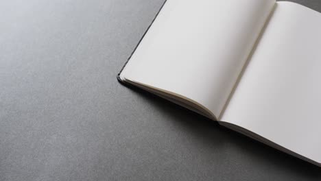 close up of open blank book with copy space on gray background in slow motion