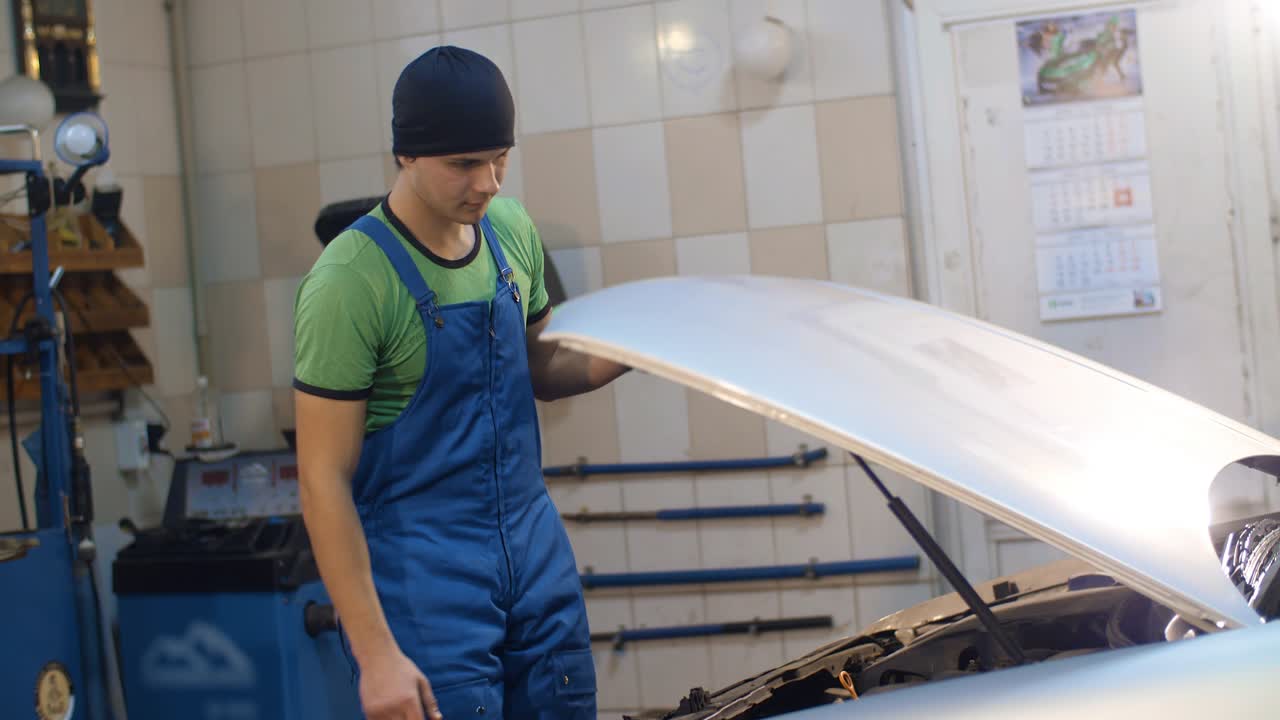 el mecánico automático abre el capó de un coche