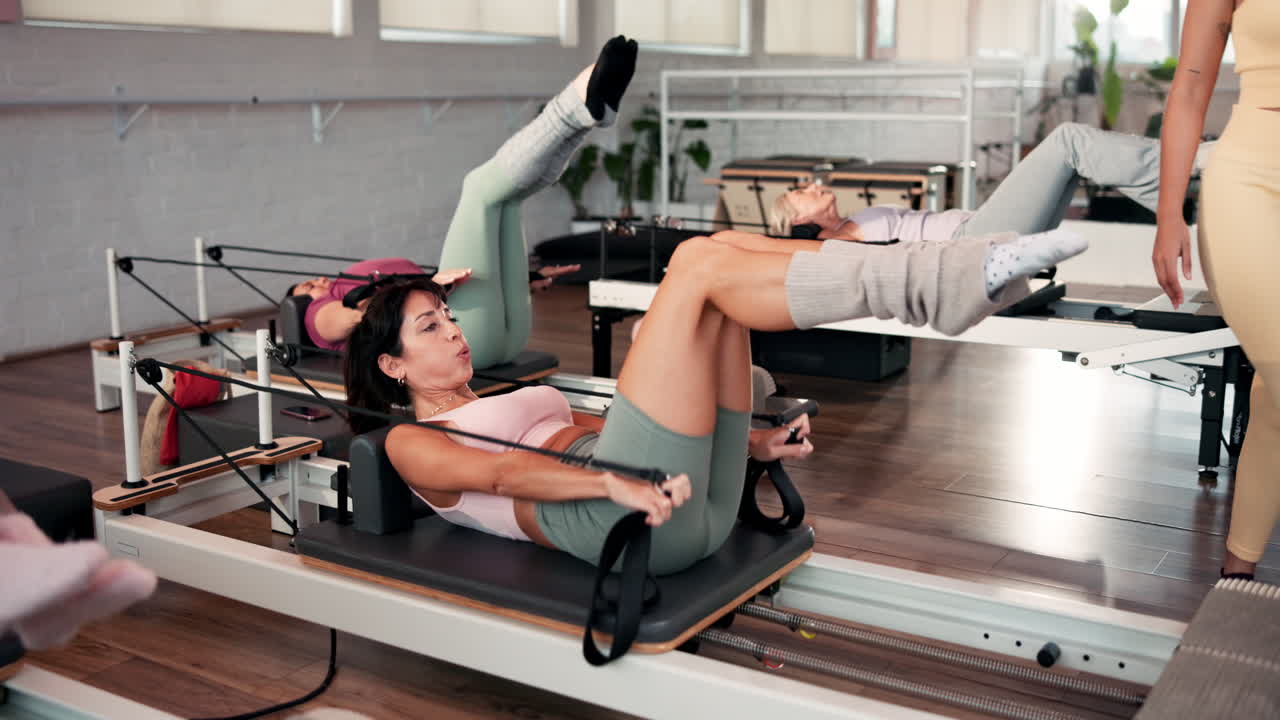 Aula de pilates com mulheres se exercitando em aparelhos reformer