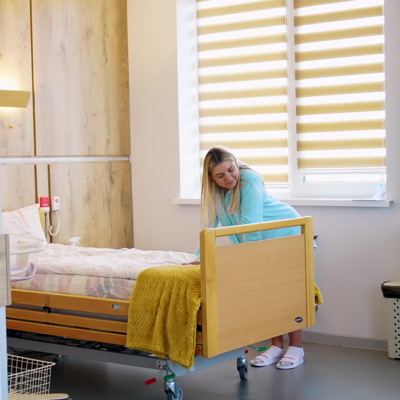 Pregnant blonde lady in the hospital ward. Lady leans on the bed to relief pain from contractions