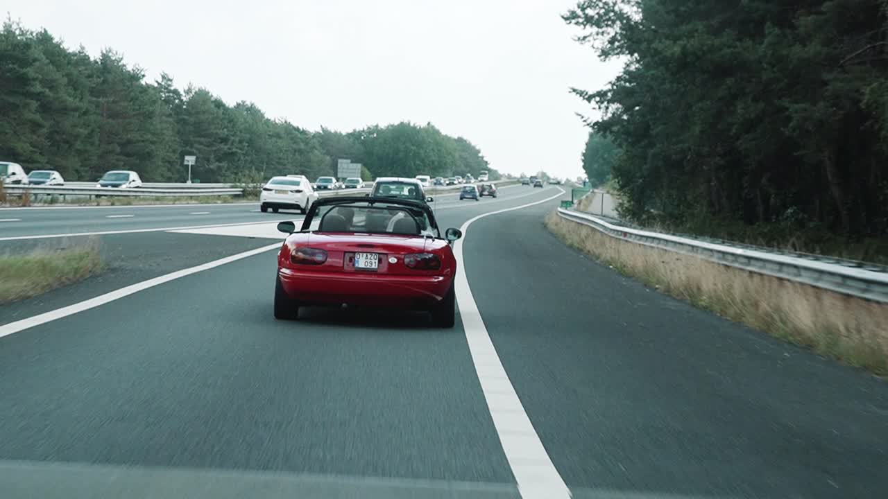 Red old timer car driving fast on to the highway of Belgium to The Netherlands.