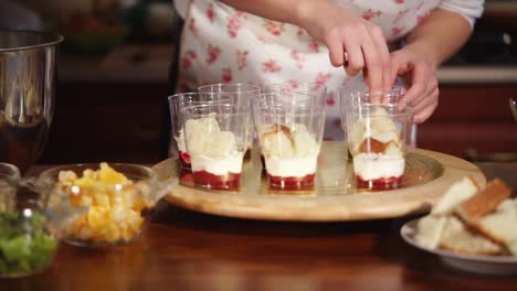 woman preparing a layered dessert trifle in glasses