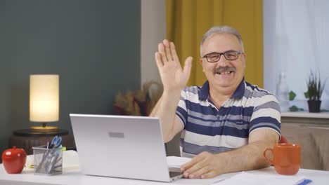 home office worker old man waving at camera.