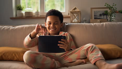 boy using a tablet on a couch at home