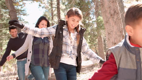 Feliz-Familia-Hispana-Balanceándose-Sobre-Un-árbol-Caído-En-Un-Bosque