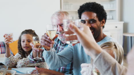 Familia-Multigeneracional-Brindando-Con-Vino-Mientras-Se-Reúnen-Para-Comer-En-Casa