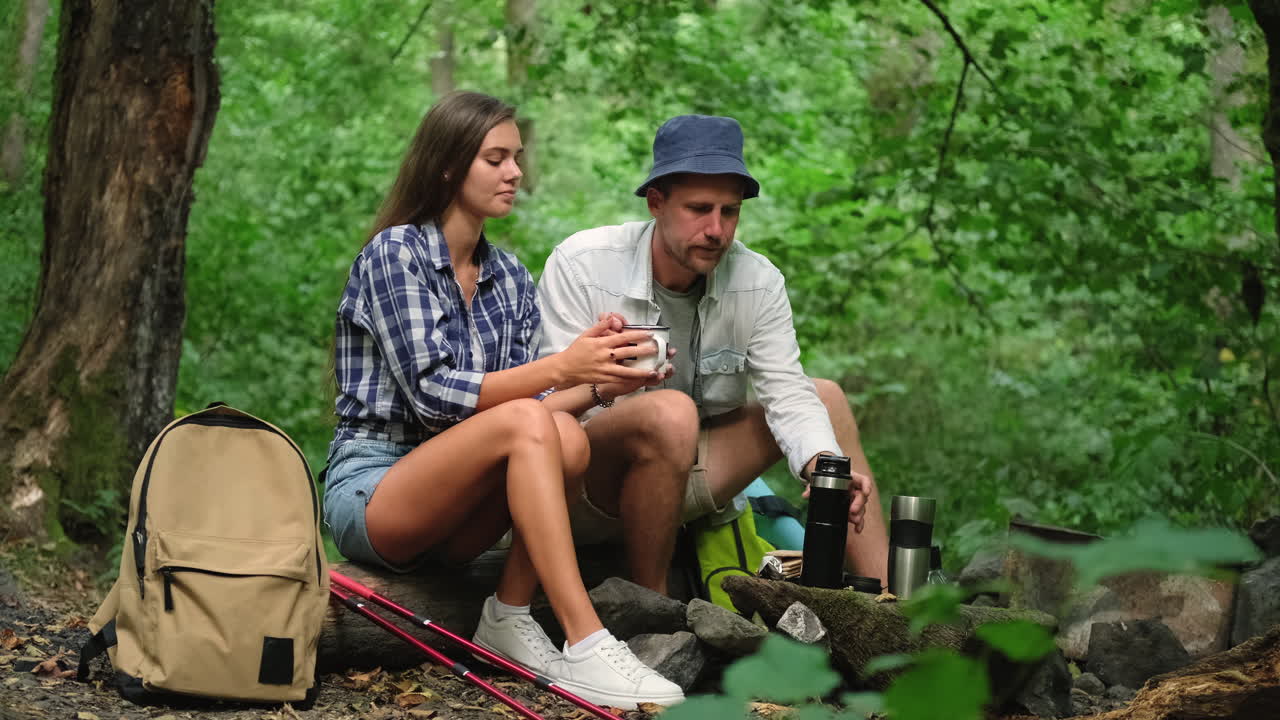 커플이 산책하고 숲에서 뜨거운 음료를 즐기고 있습니다.