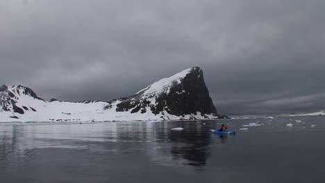 a man paddles a kayak through a gorgeous arctic or antarctica region