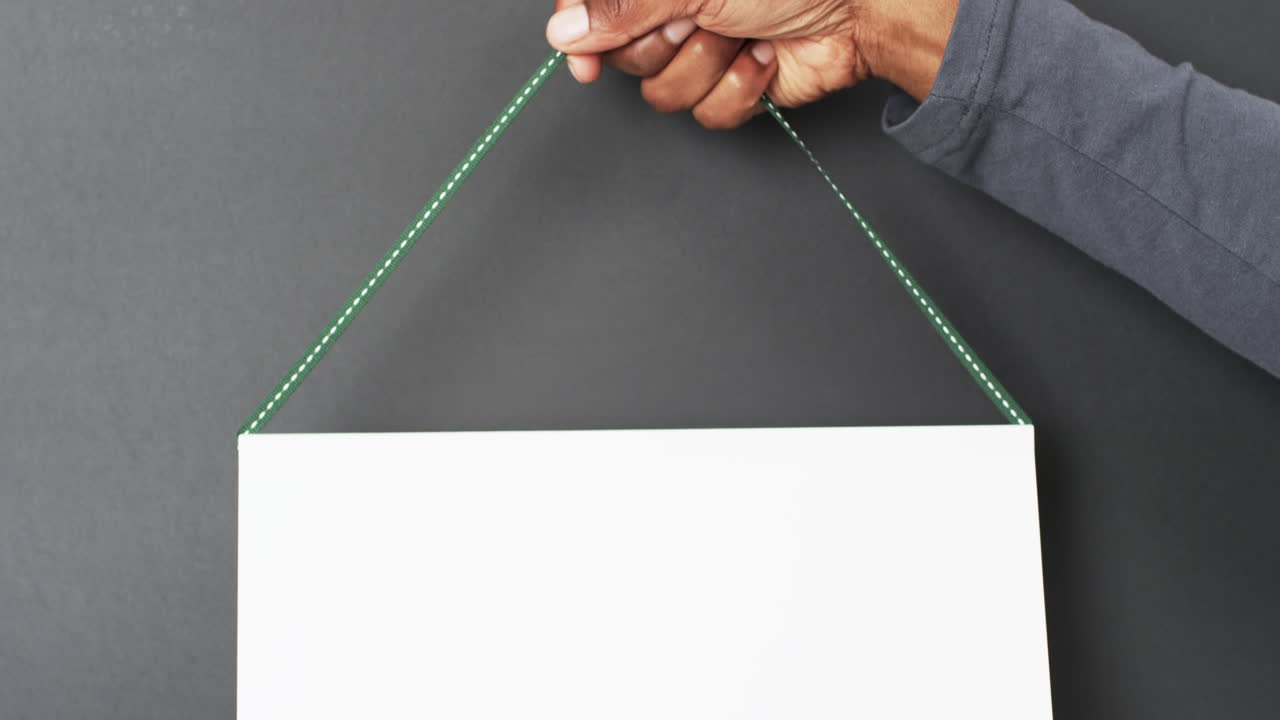 백색 빈 페이지, 회색 배경에 복사 공간을 가진 아프리카계 미국인 남자의 손의 비디오