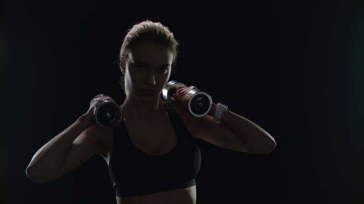 Fit girl posing with dumbbells on shoulders