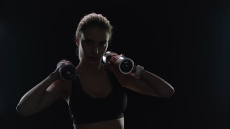 fit girl posing with dumbbells on shoulders