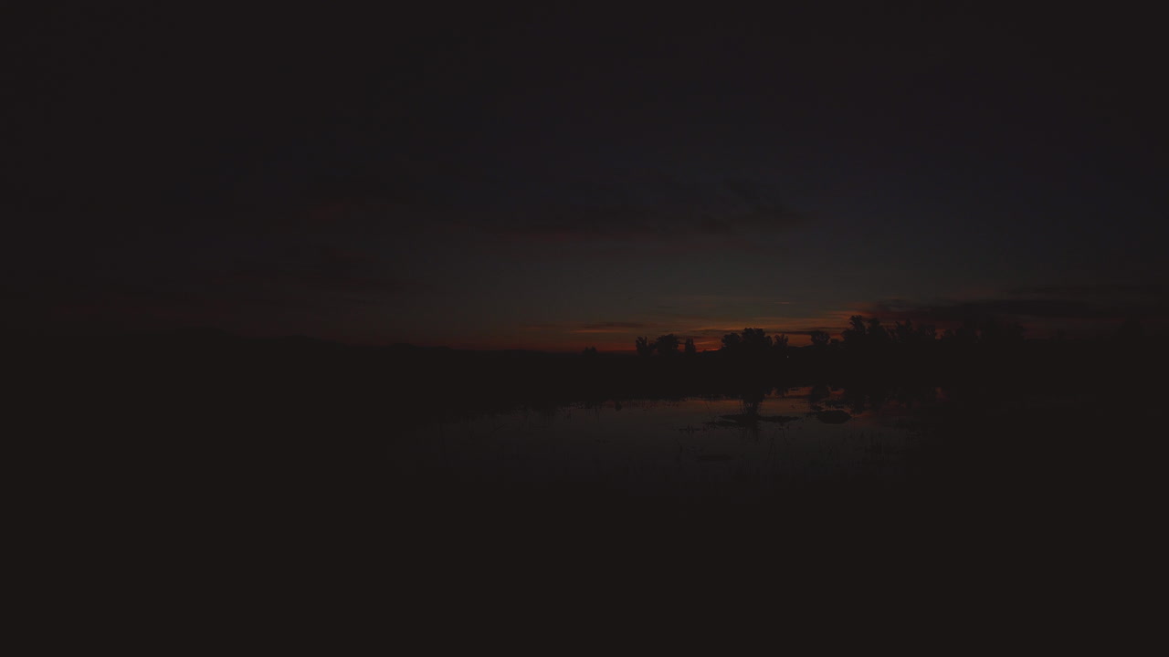 Golden Hour Sunset in California. Reflections from a pond in the foreground, the clouds and glow are presented as the sun goes down below the horizon. Located in a prairie.