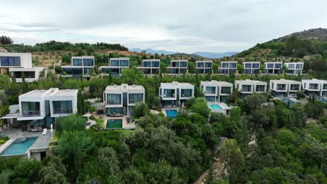 modern buildings with pools by green hills at sarande, albania, aerial pan