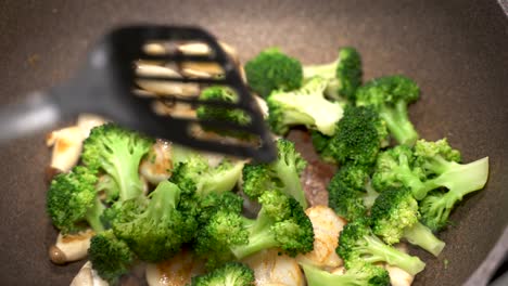 delicious scallops, broccoli and mushrooms being fried cooked in a large pan