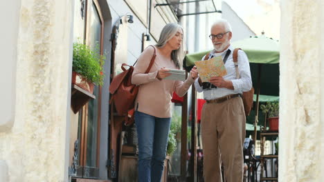 couple with tablet computer and a map standing at the cafe terrace as tourists