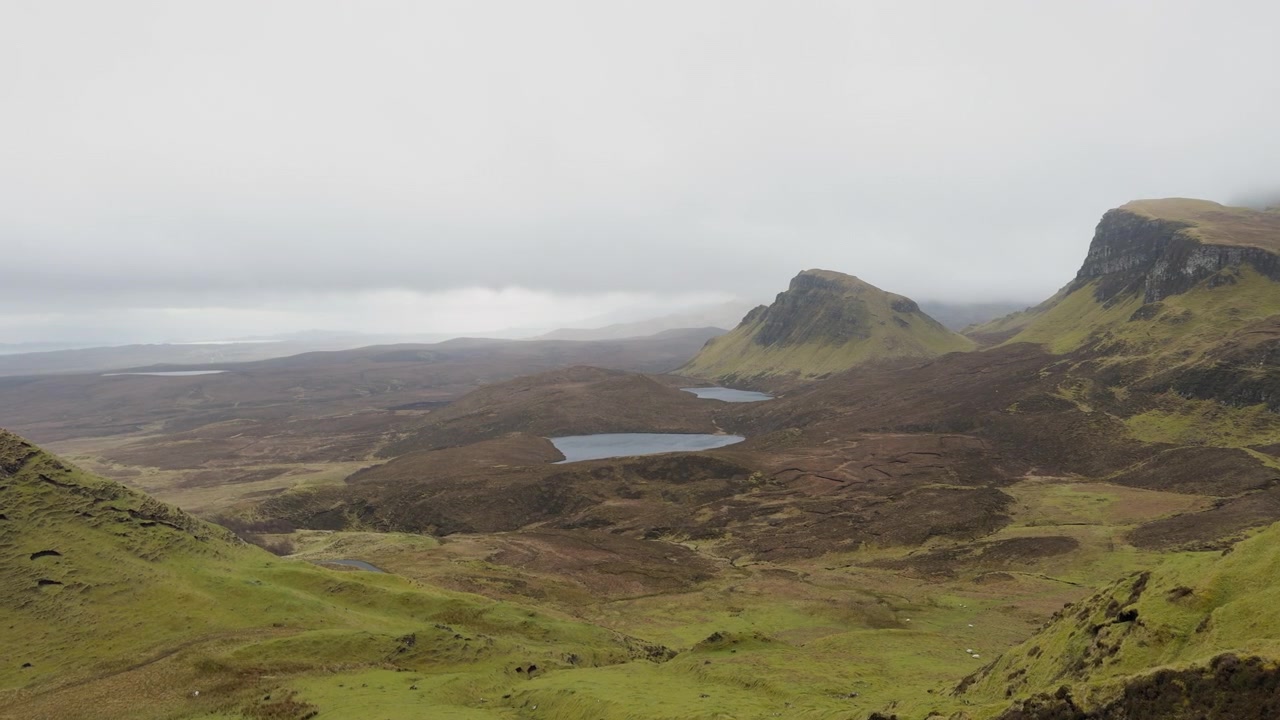 Panoramabilde fra bakkenivå av The Quiraing, Isle of Skye. Dramatiske jordskredformasjoner, fjellsjøer og topper under tunge skyer. Stemningsfullt skotsk opptak