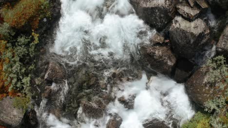 a massive water current powered by a melting glacier is running over gargantuan rocks, pushing itself, and creating foam