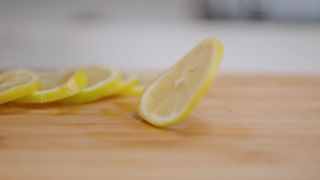 Freshly-sliced-bright-yellow-lemon-coin-spinning-in-slow-motion-on-cutting-board-in-kitchen